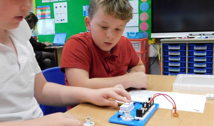 Two boys working with electric circuit kit