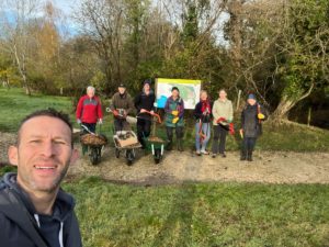 Group of volunteers with wheelbarrows and tools to work outdoors in woodland