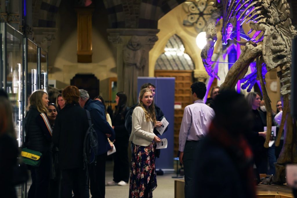 Gathering of people at night (low lighting) in Oxford University Museum of Natural History, among exhibits