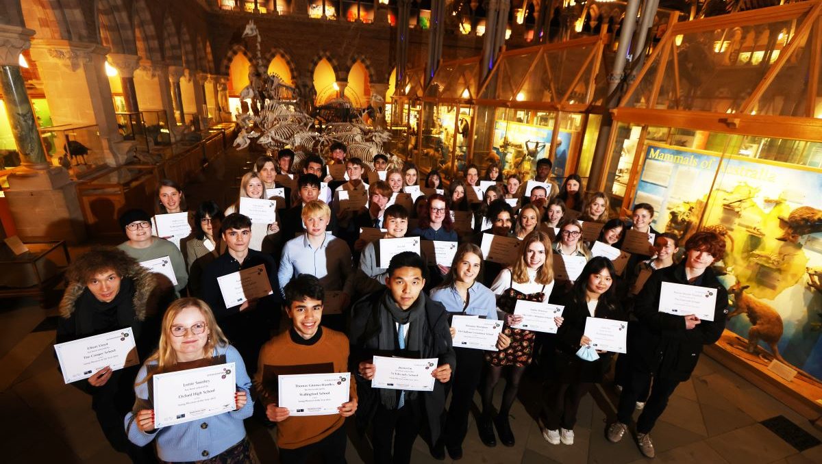 group of students with certificates in setting of museum at night