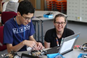 Teenager and adult in front of laptop with small robotic car