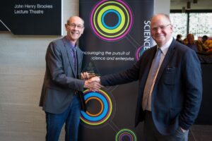 Graham Quelch shakes had with Steve Burgess in front of Science Oxford pull-up banner