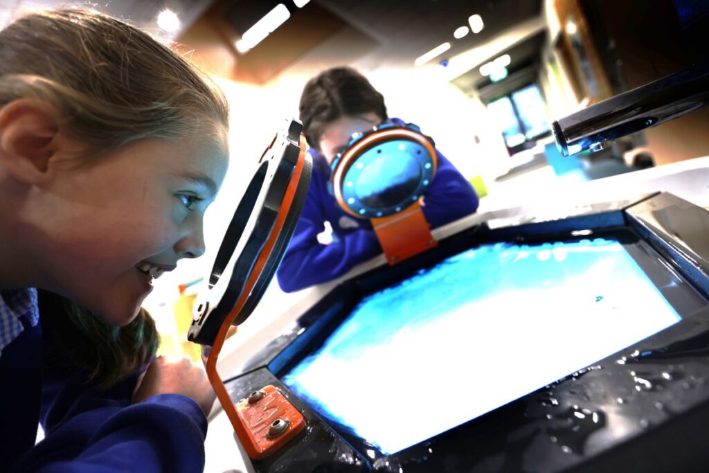 Two children peering through looking glass at water freezing exhibit
