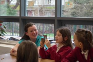 Adult sitting and listening to a group of children at a table