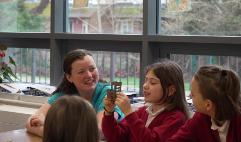 Adult sitting and listening to a group of children at a table