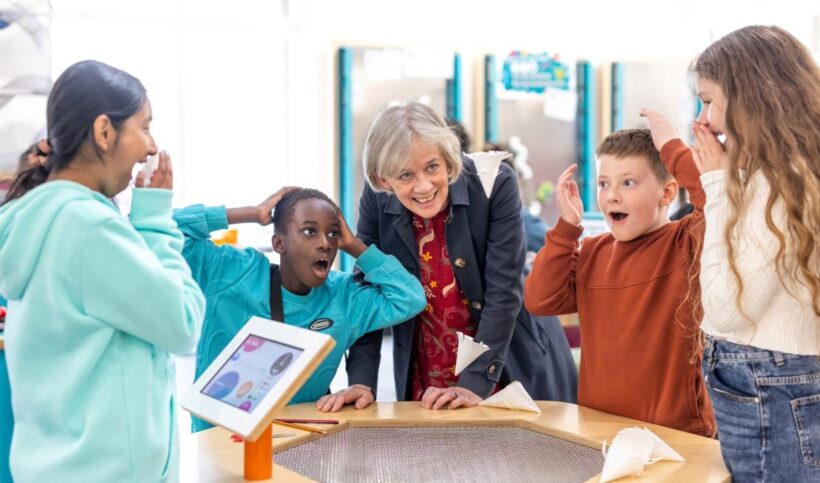 Group of 4 children and 1 adult around science exhibit, showing gasps of delight