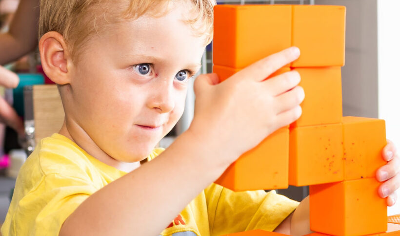 child with orange building blocks