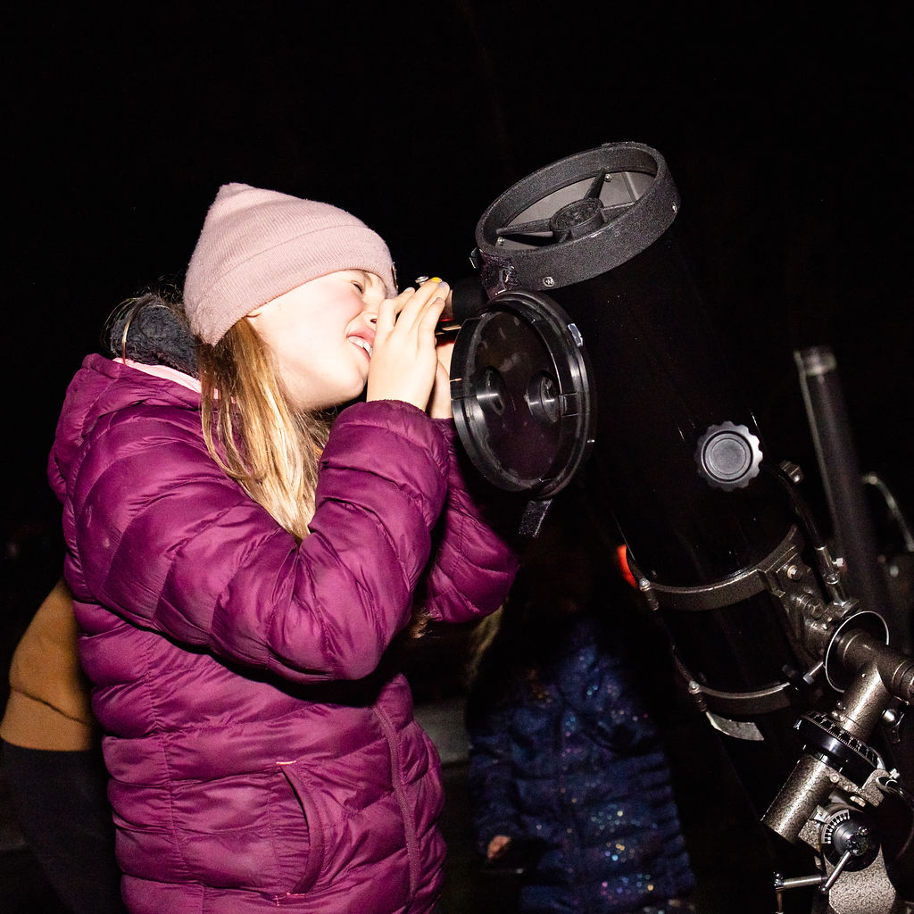 child views the night sky through large telescope